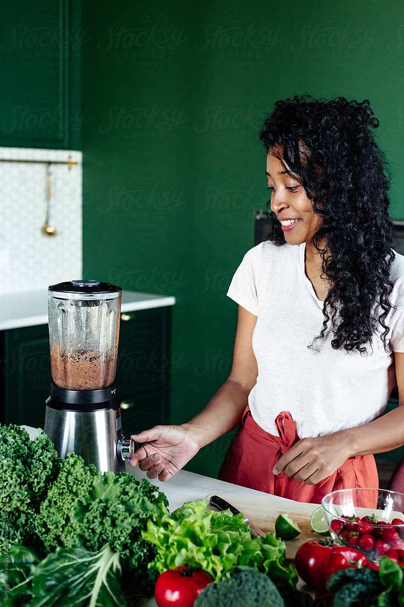 Black woman using blender in kitchen