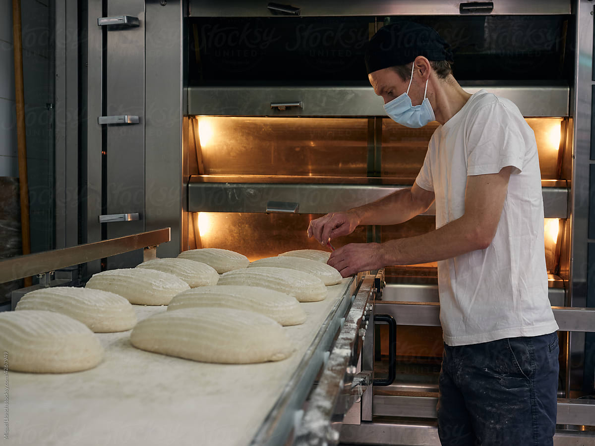 Baker at work preparing bread loafs for oven