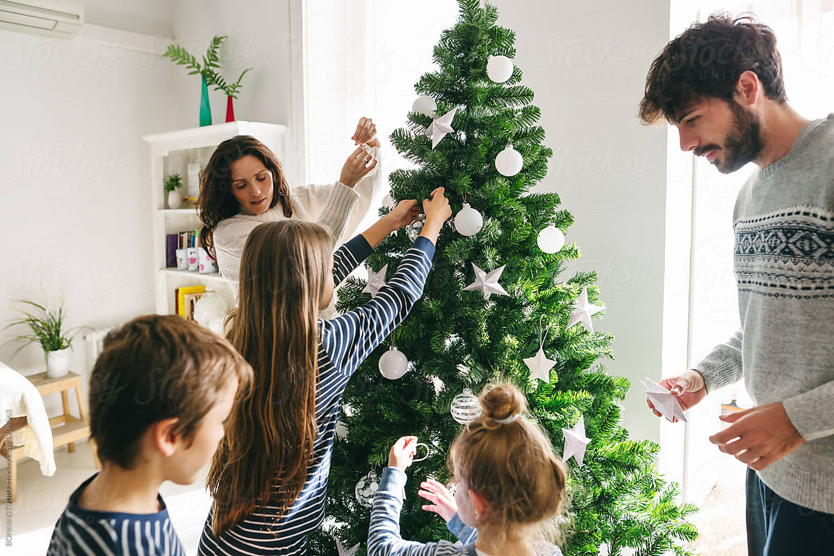 Family decorating Christmas tree at home. - Stock Image - Everypixel