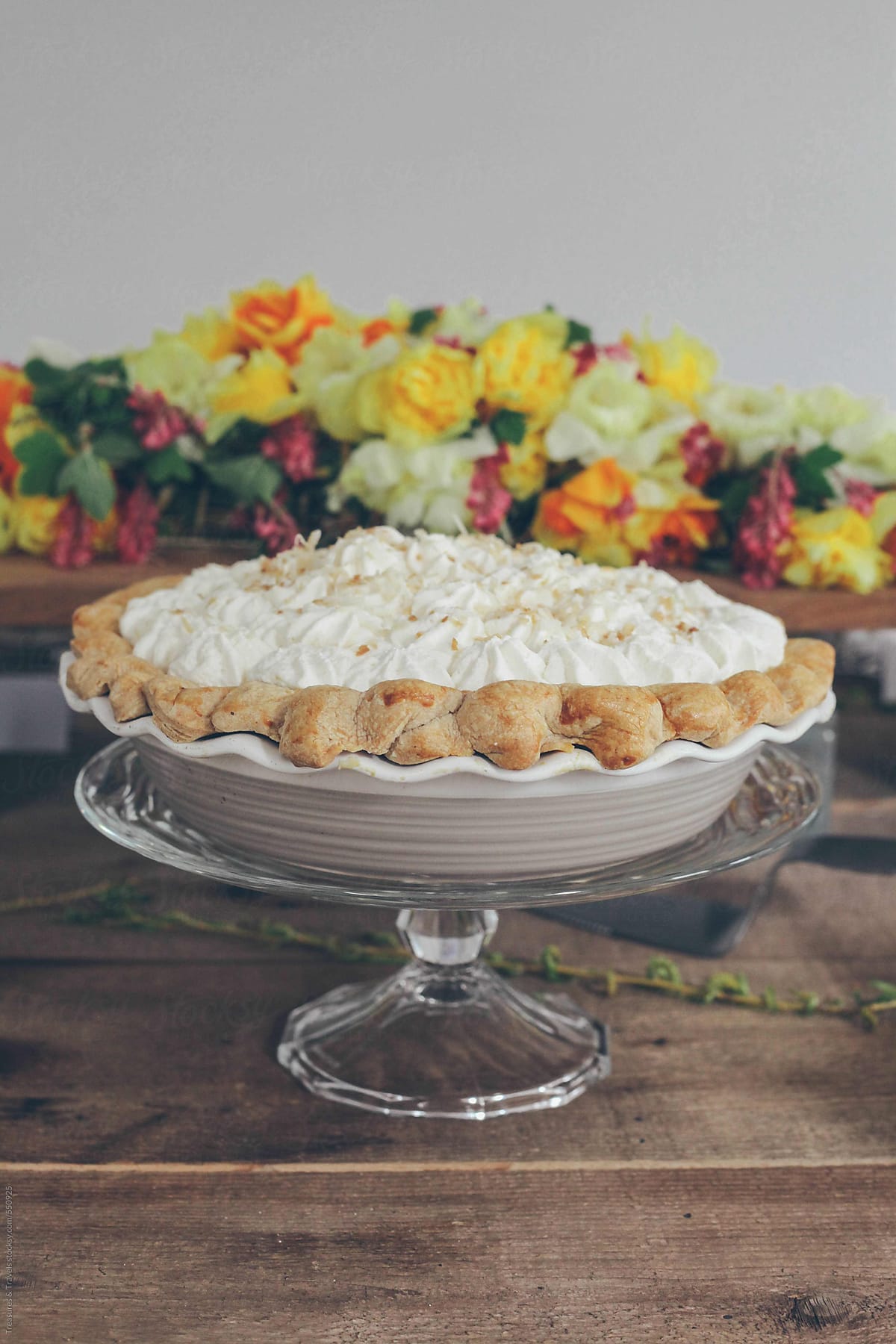 Coconut Cream Pie on a pie dish in front of flowers