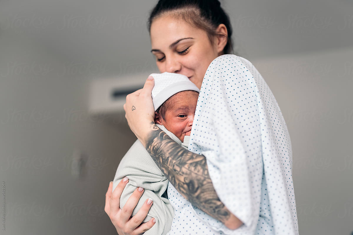 Mother kissing Newborn In Hospital room