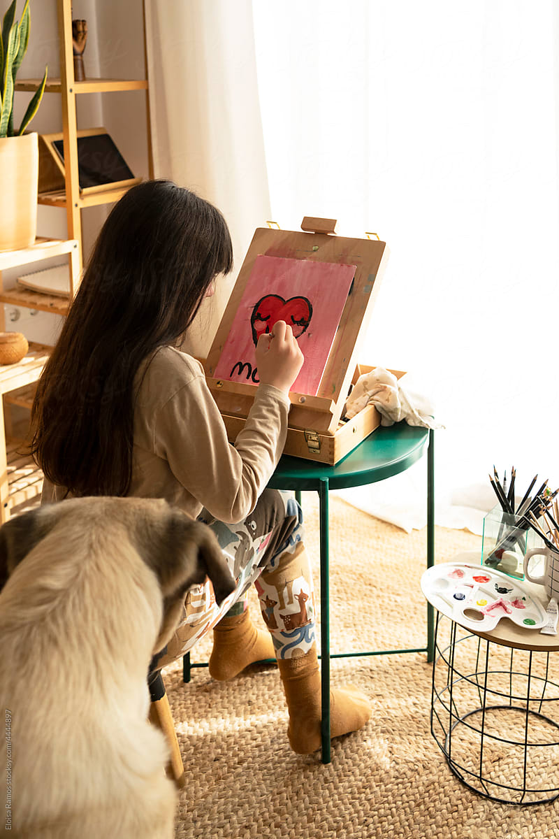 Kid with her dog painting at home