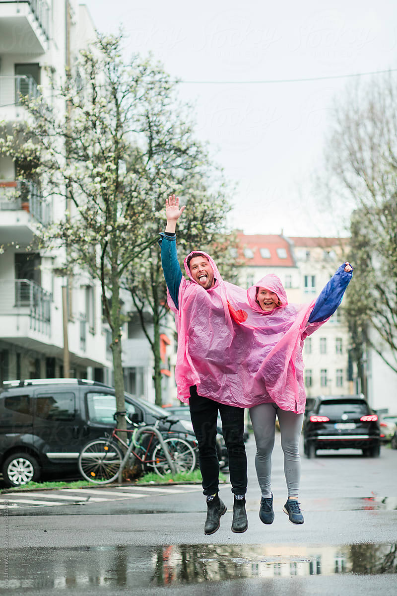 Couple jumping in rain puddle