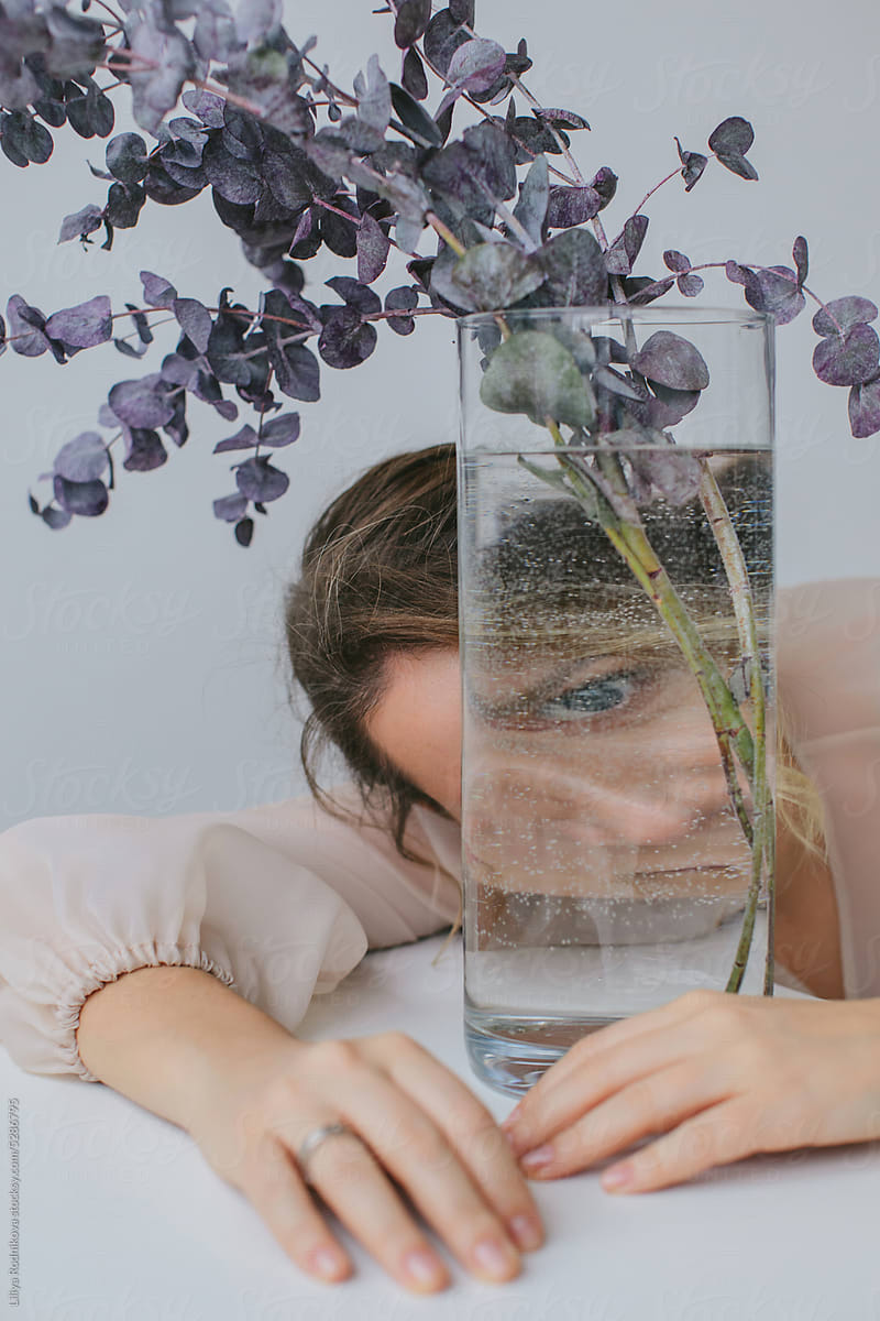 woman looking through glass vase with eucalyptus