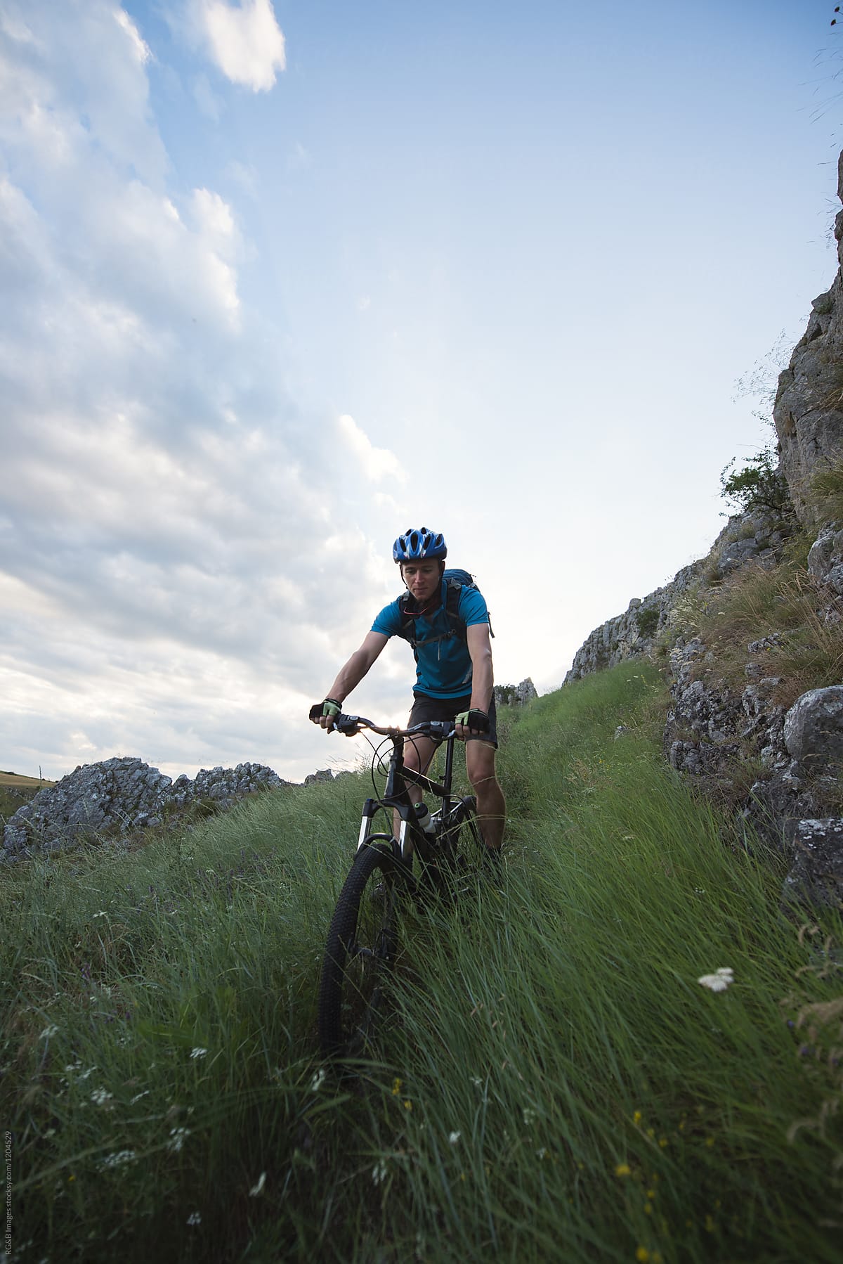 Cyclist man riding mountain bike through a tall grass meadow
