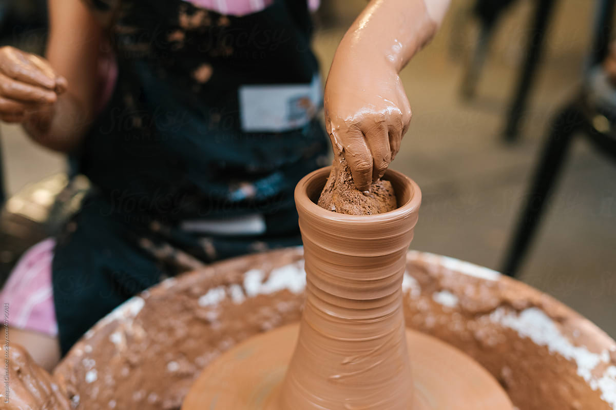Anonymous person working with clay at pottery wheel