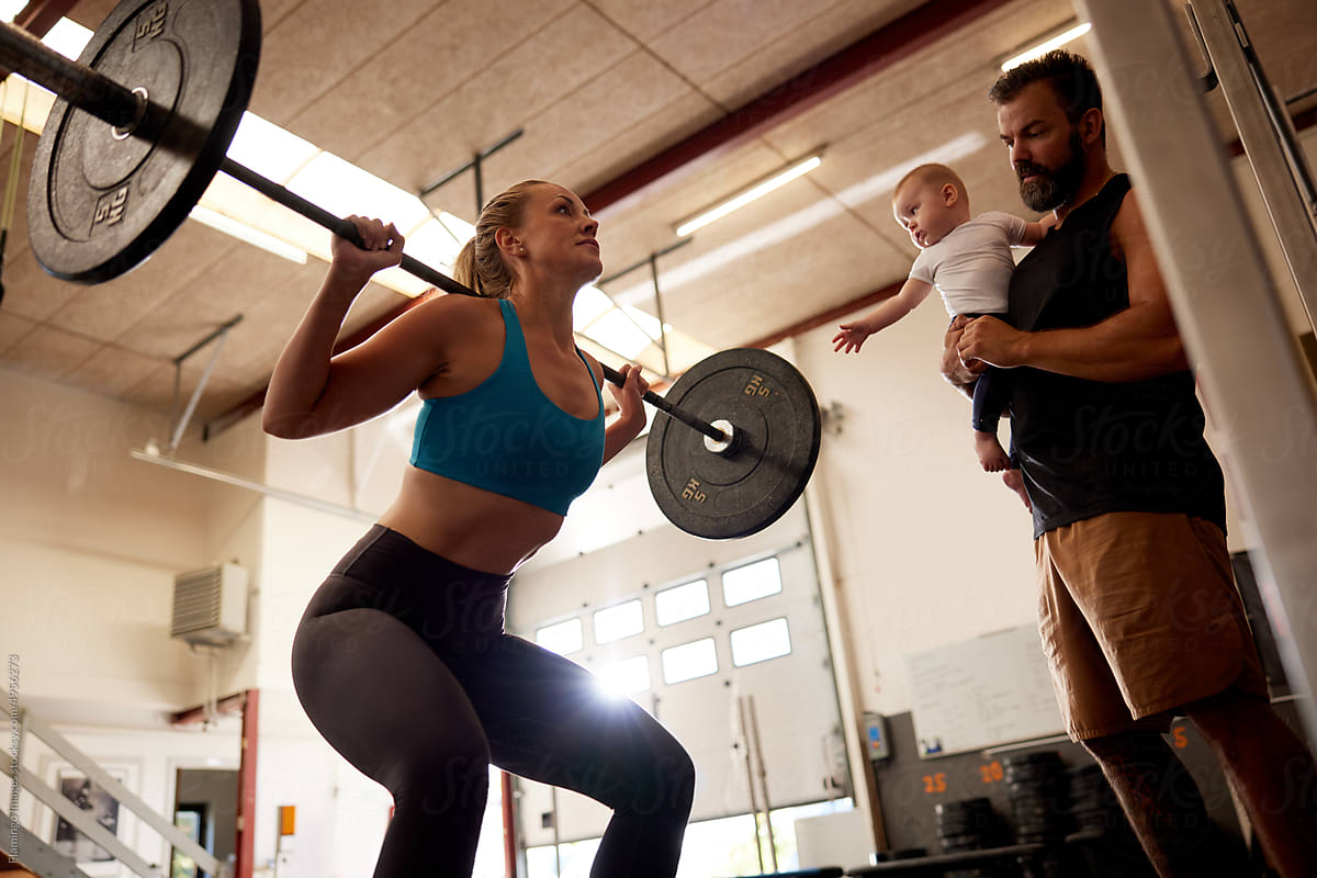 Woman weightlifting with her family watching