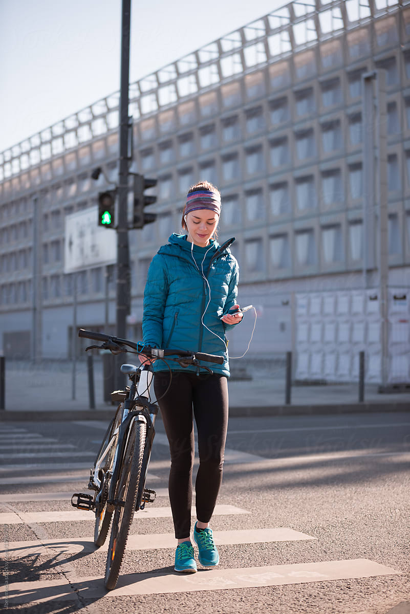 Woman walking her bike on the crosswalk in the morning