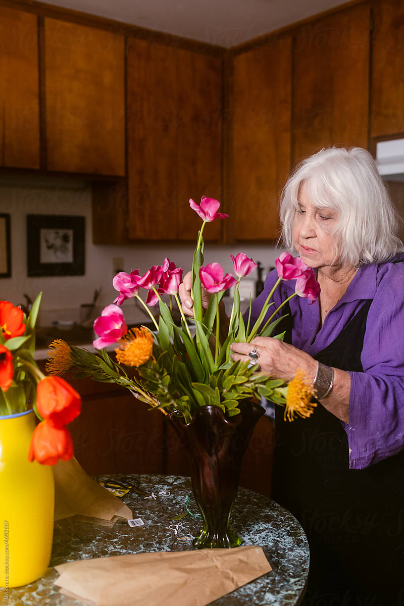 Grey-haired  senior preparing vase of flowers