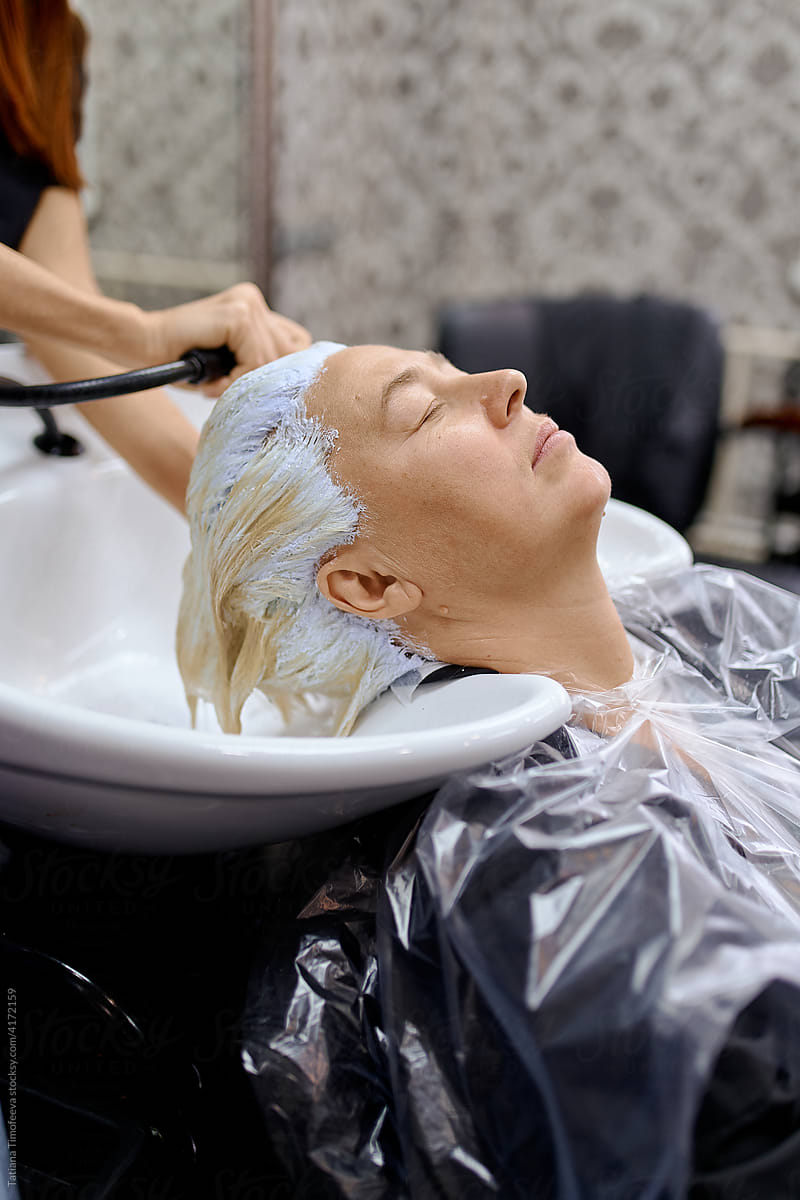 the hair master washes the client\'s head from hair dye