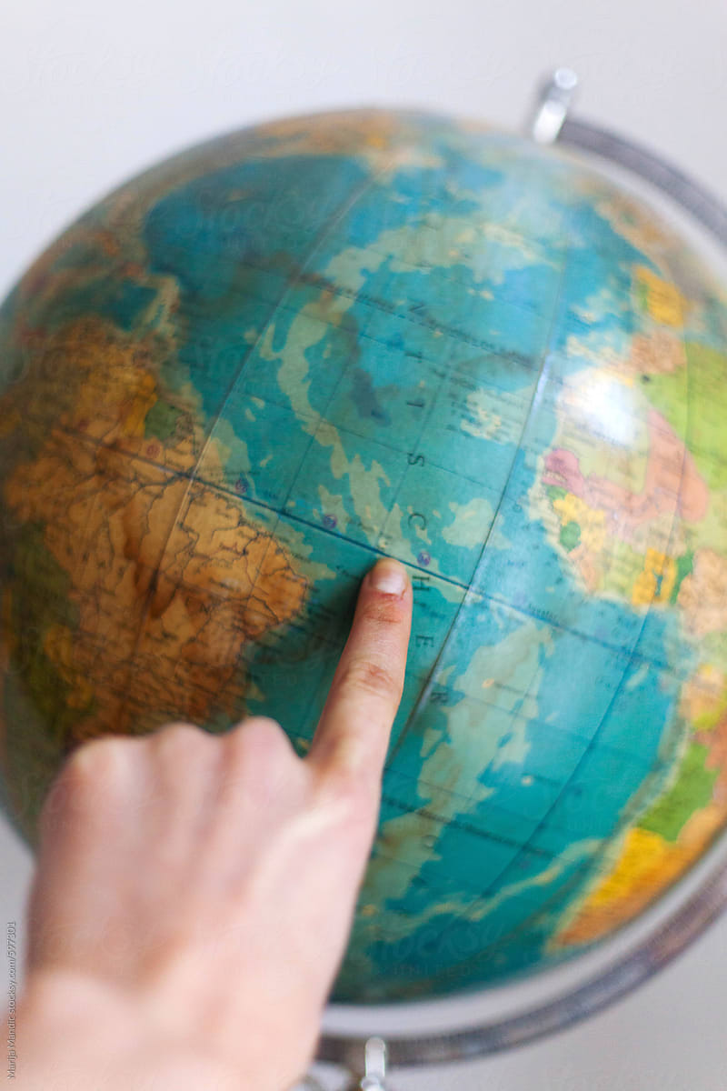 Female finger showing a part of the world on an old globe