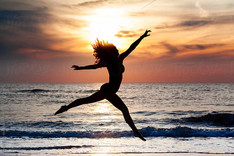 Silhouette of a teenage girl jumping gracefully on the beach