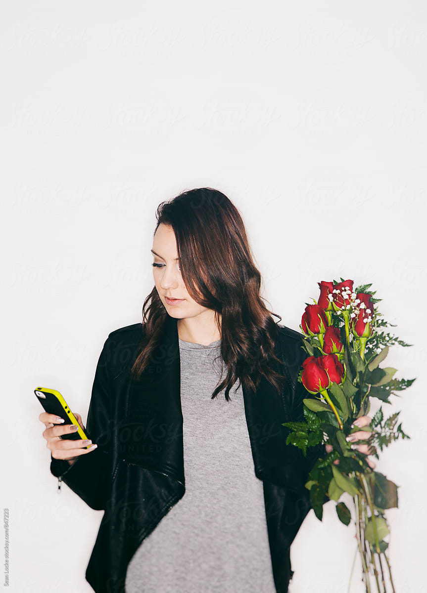 Valentine: Woman Reading Cell Phone While Holding Rose Bouquet