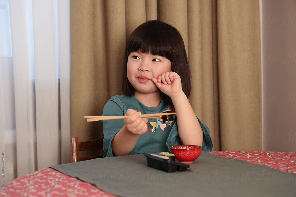 little girl eating sushi rolls at home