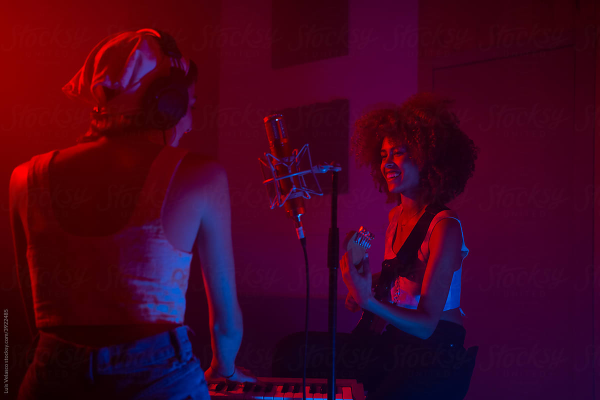Two Young Girls Playing Music In A Red And Blue Studio.