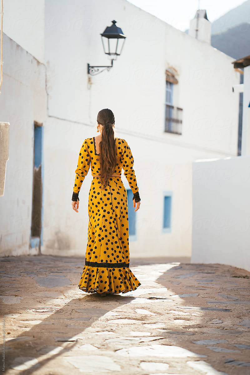 Woman in flamenco dress walking on paved street