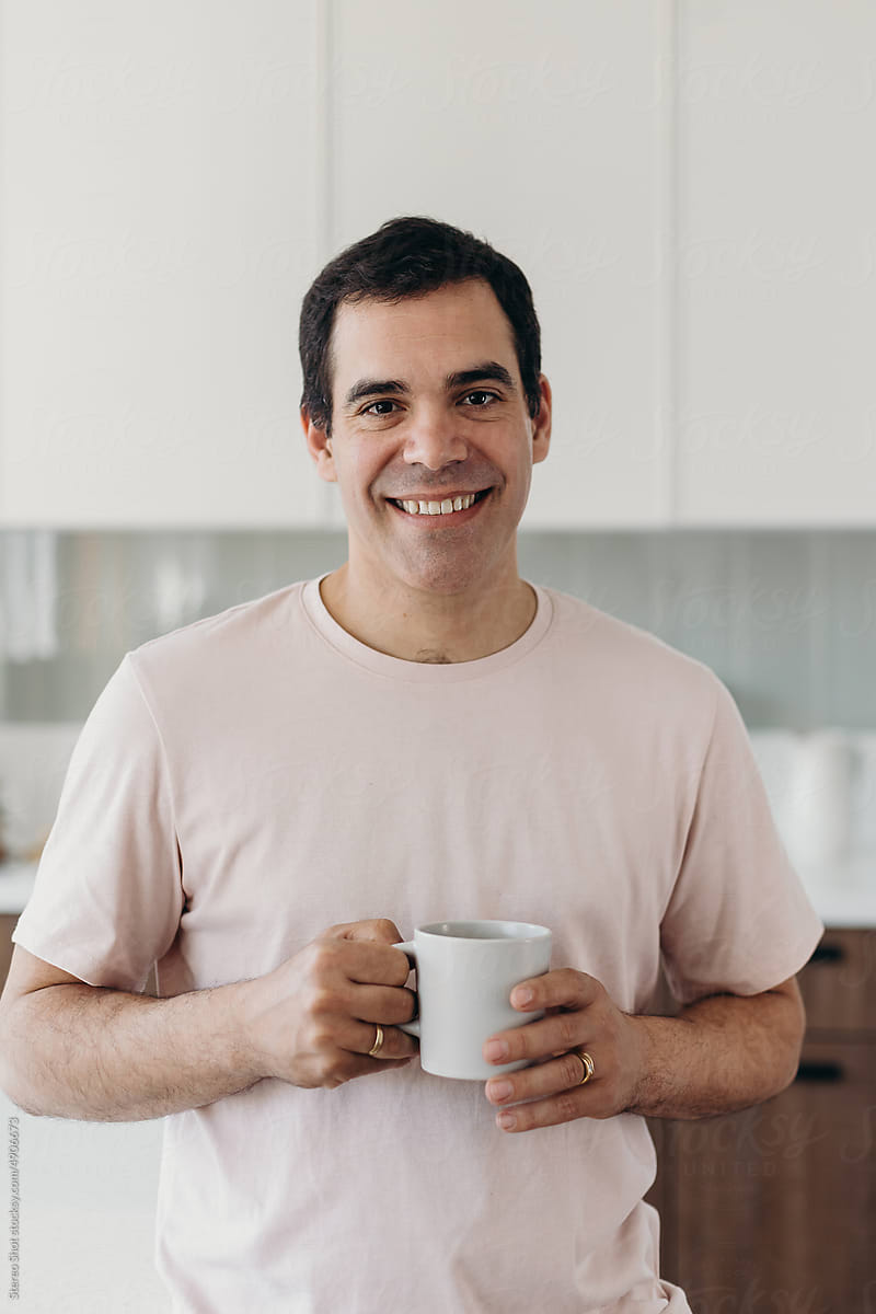 Cheerful Hispanic man with coffee at home