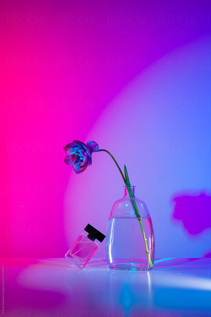 Glass perfume bottle with tulip flower in neon lights