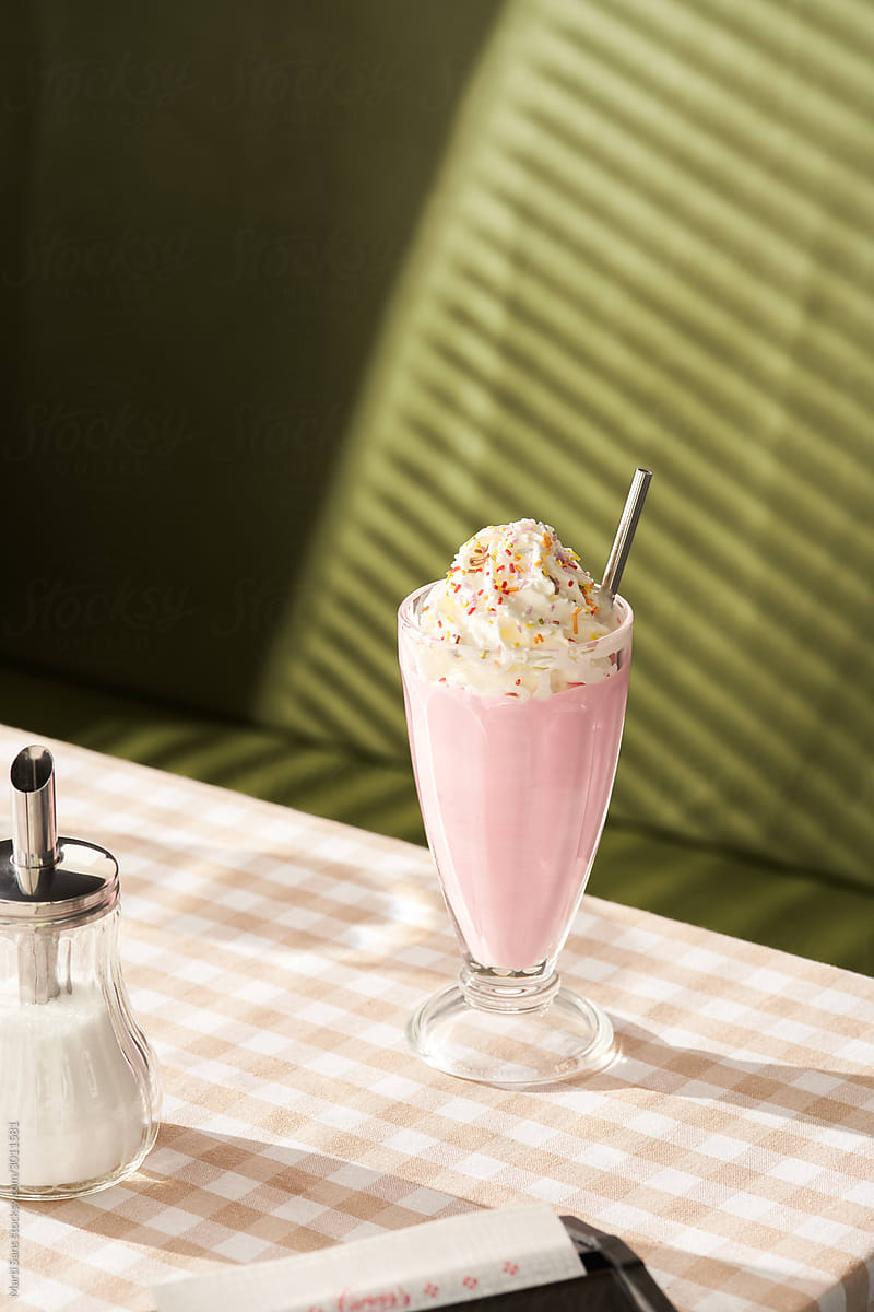 Strawberry milkshake on table with sugar bowl