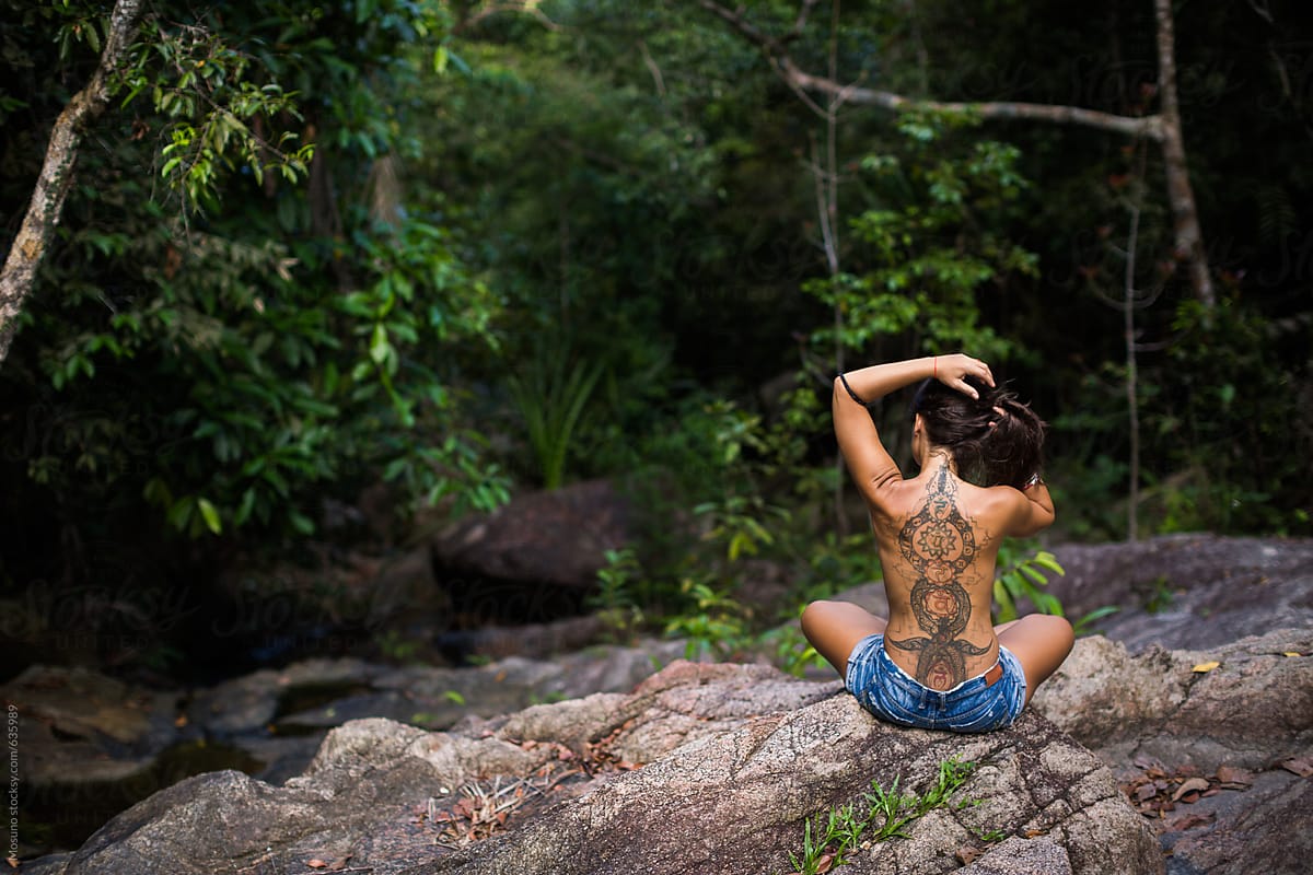 Tattooed Young Woman Sitting in the Jungle