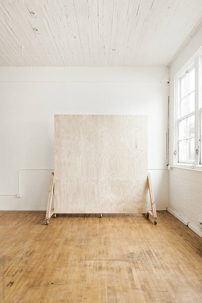 plywood backdrop wall in white natural light studio with large windows