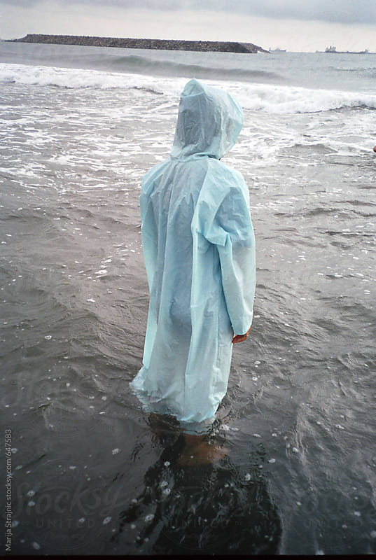 Blue raincoat standing in the ocean