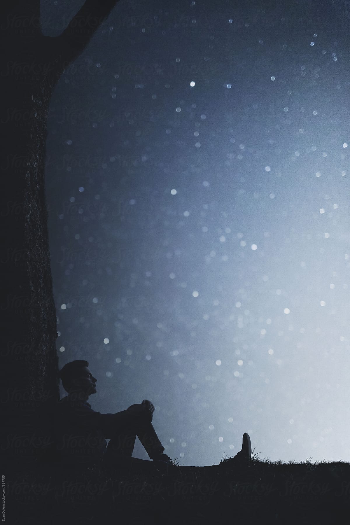 Man Sitting Against Tree Under Stars