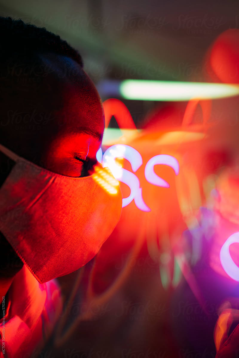 Black man in mask in dark room with neon lights