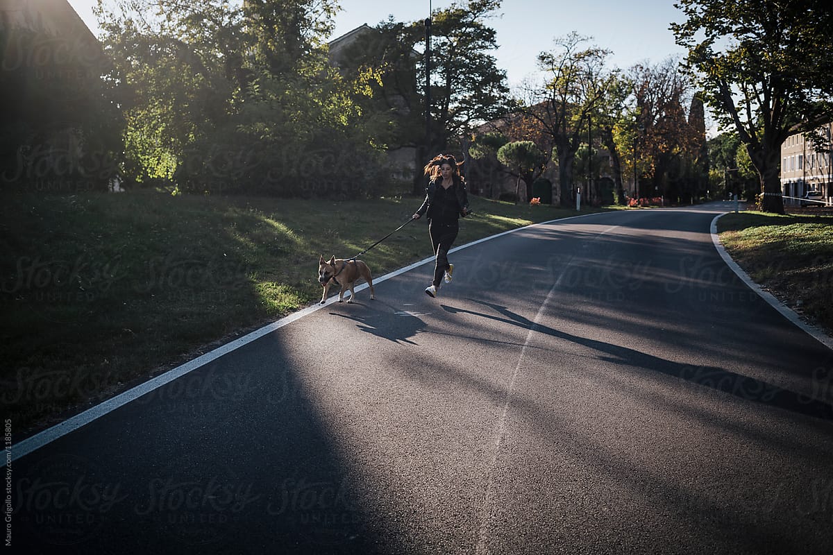 Woman runs on a street with her dog