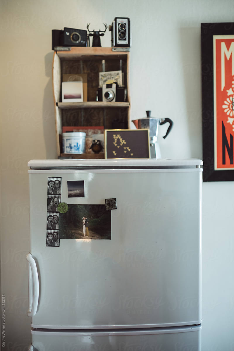 A tiny refrigerator with knick knacks and pictures on it