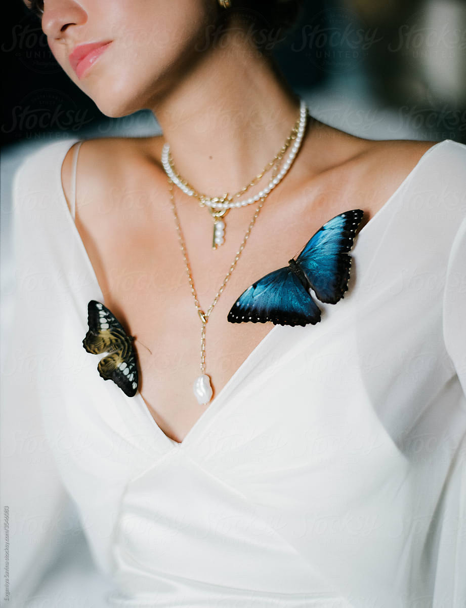A portrait of the bride  wearing white dress with butterflies on her chest