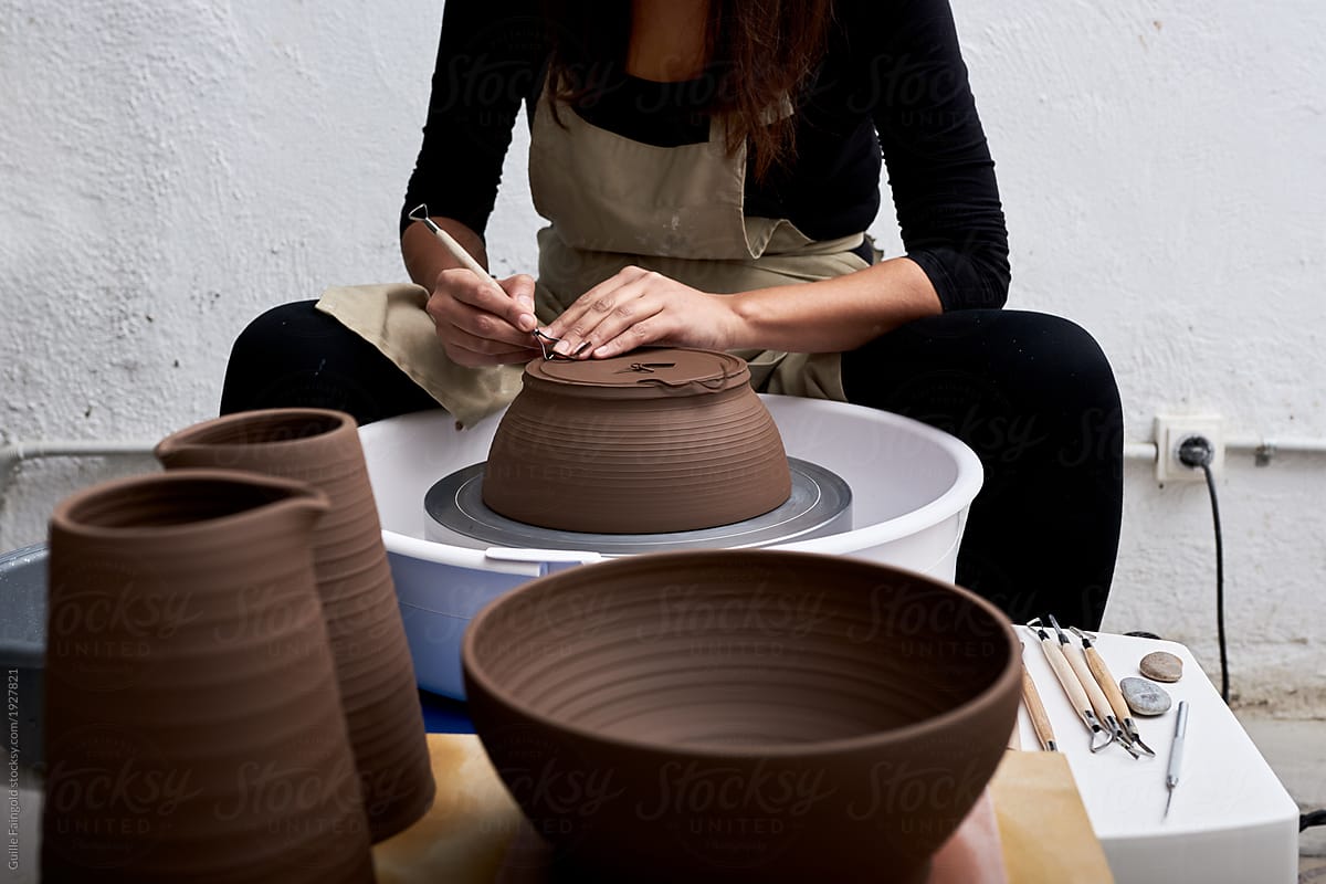 Crop artisan craving pottery on wheel