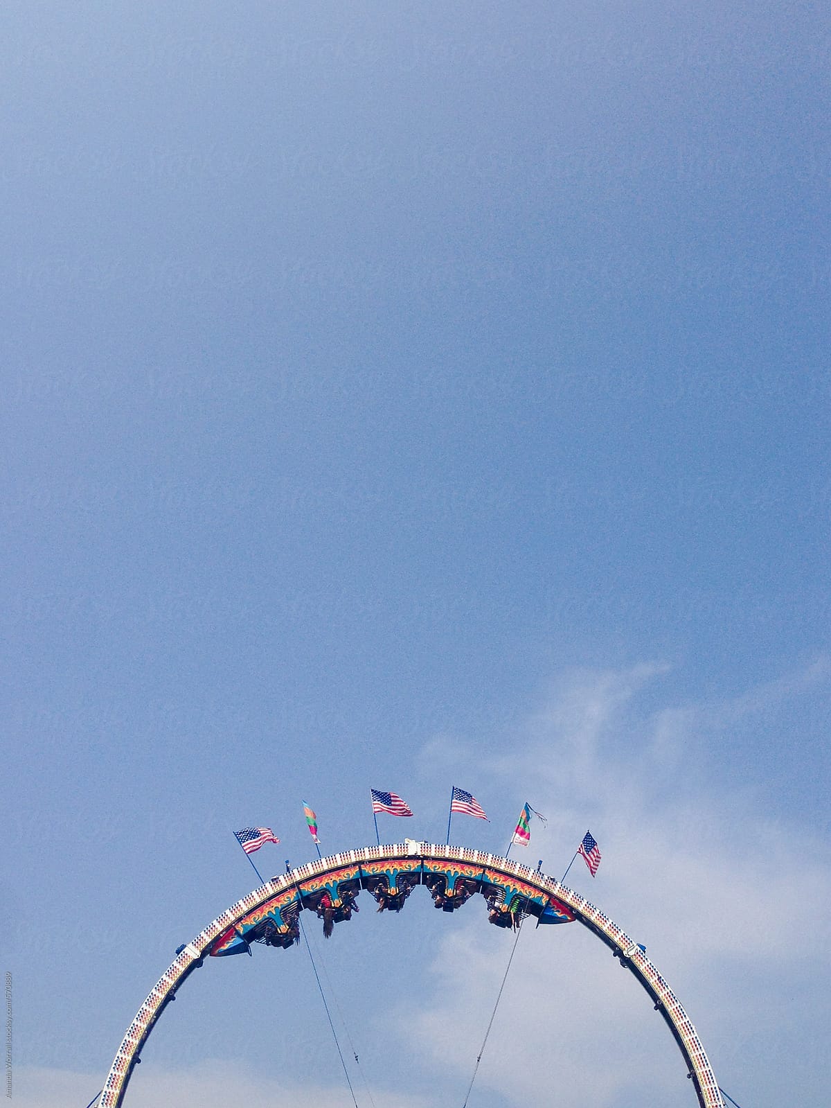 Circular carnival ride with American flags against a blue sky