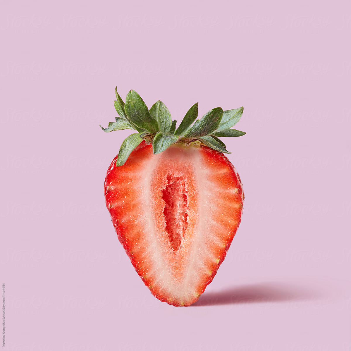 Ripe organic strawberries with green leaves on a pink background