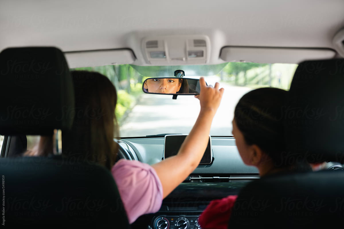 Young woman moving her car\'s rear view mirror