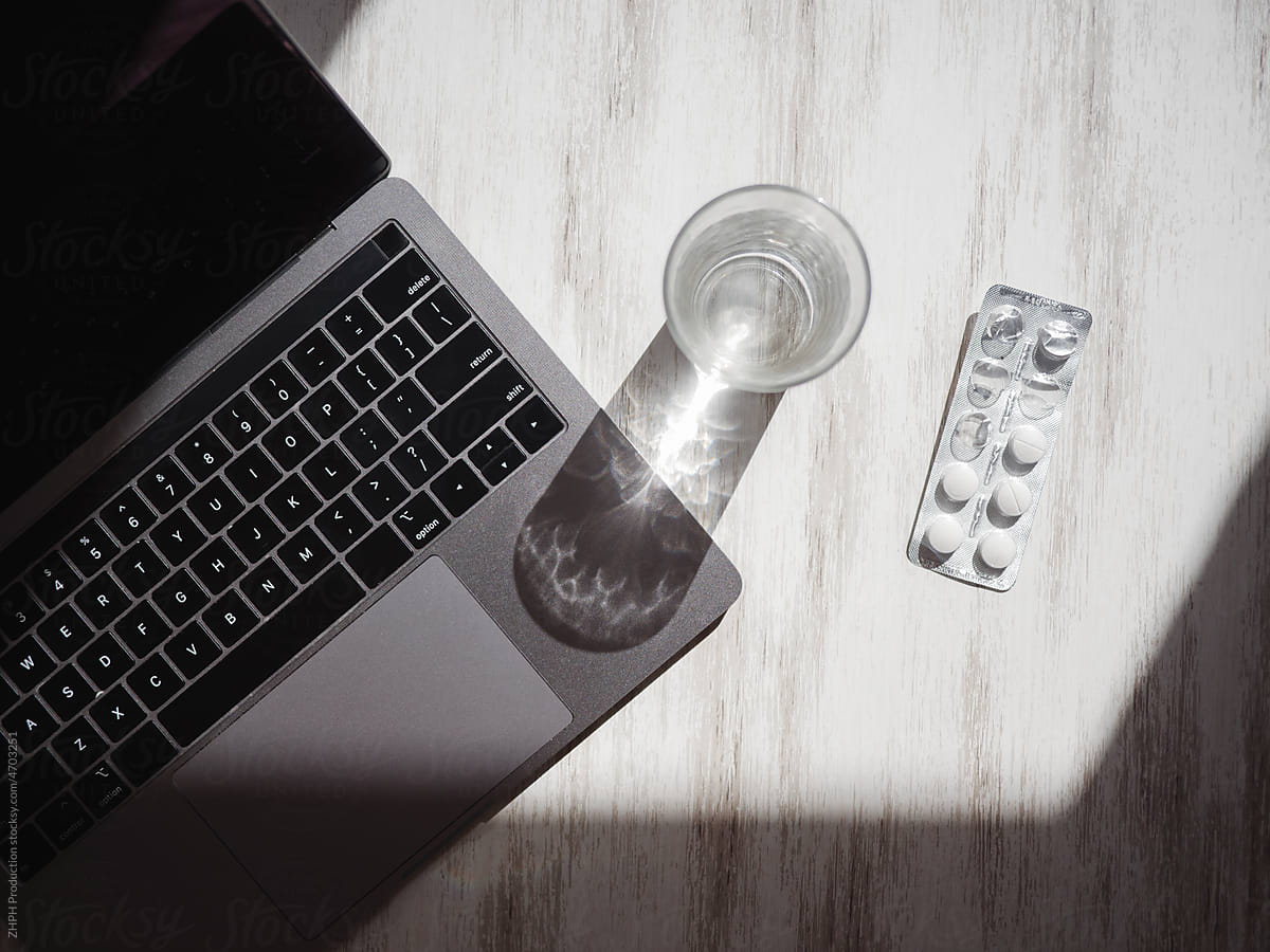 Still-life shot with laptop, pills and glass of water