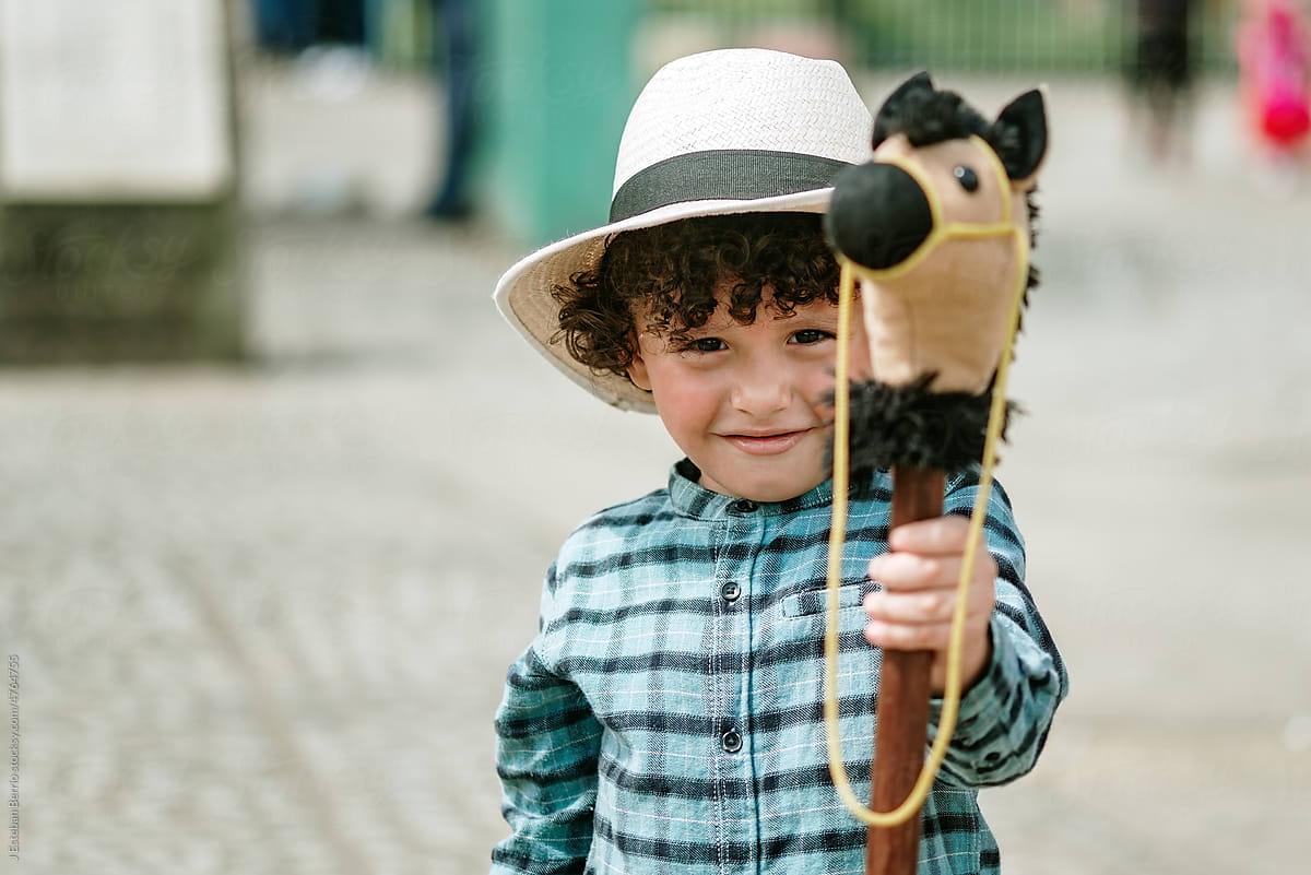 Portrait of curly-haired child holding toy in front