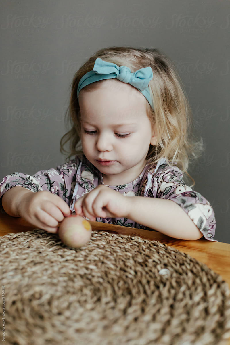 Little girl decorating egg with sticker on Easter