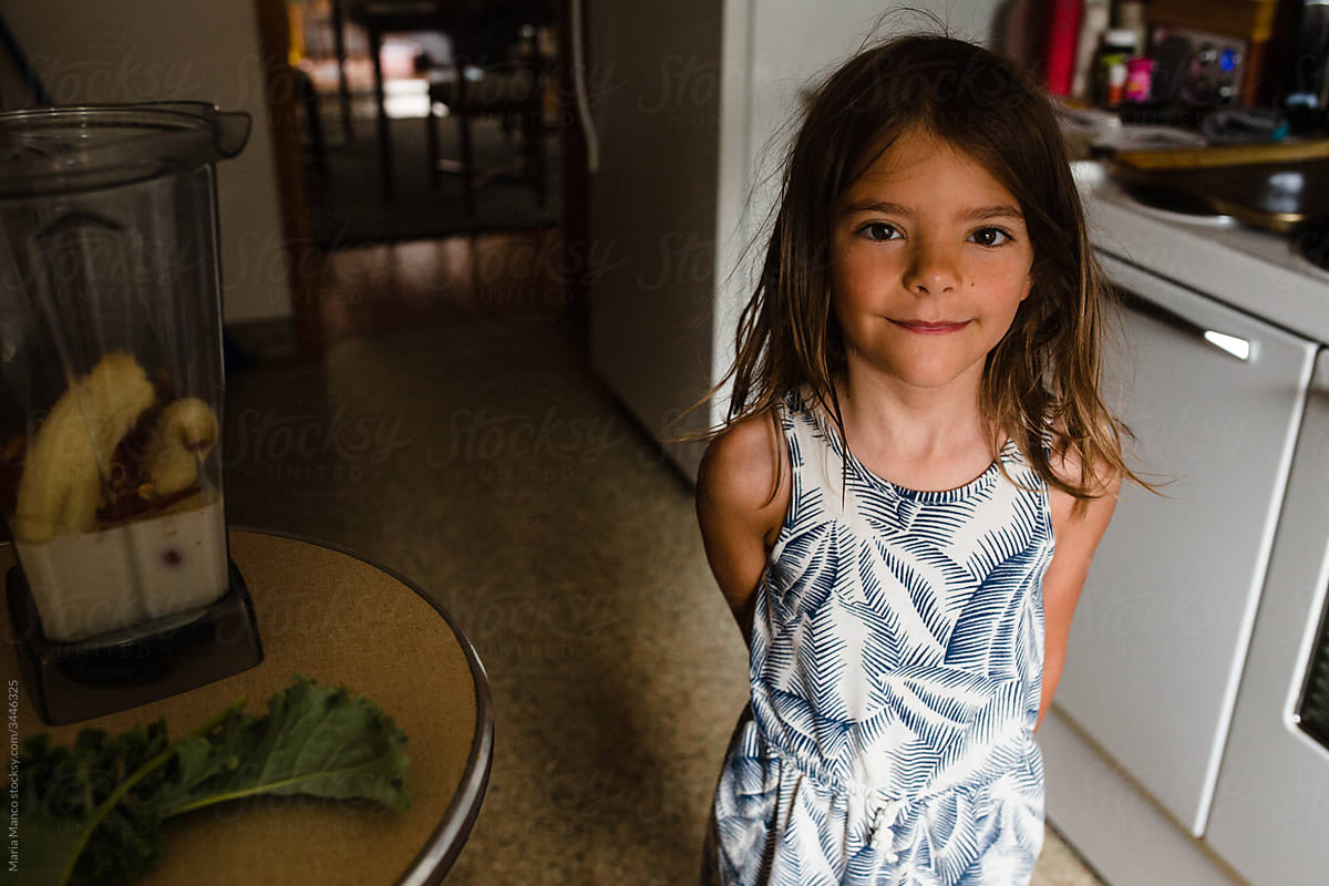 a girl stands in the kitchen by fresh fruit