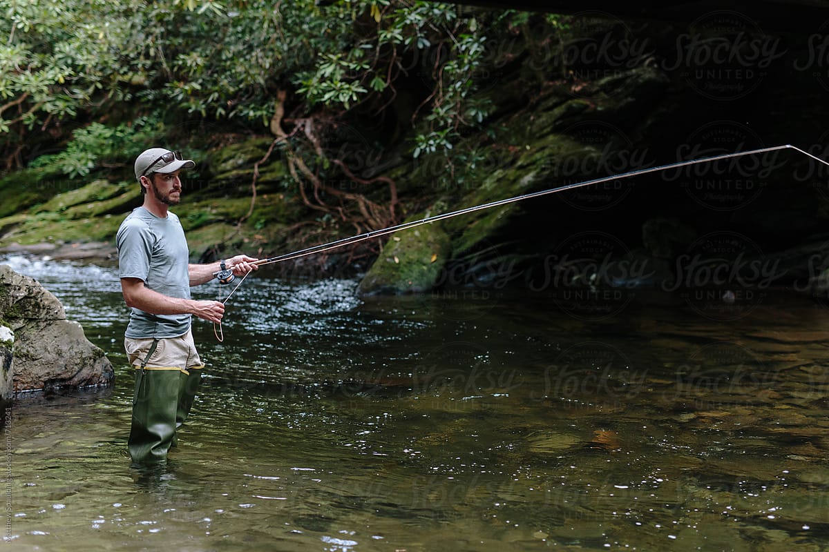 Man Fly-fishing In Clear River Trying To Catch Fish by Stocksy Contributor  Matthew Spaulding - Stocksy