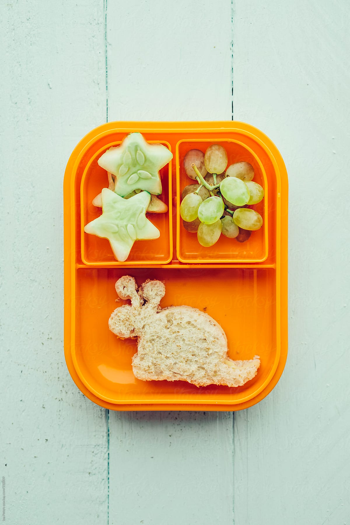 Food: Childrens' school snack, snail-shaped sandwich with cheese and tomato, star-shaped cucumber and grapes