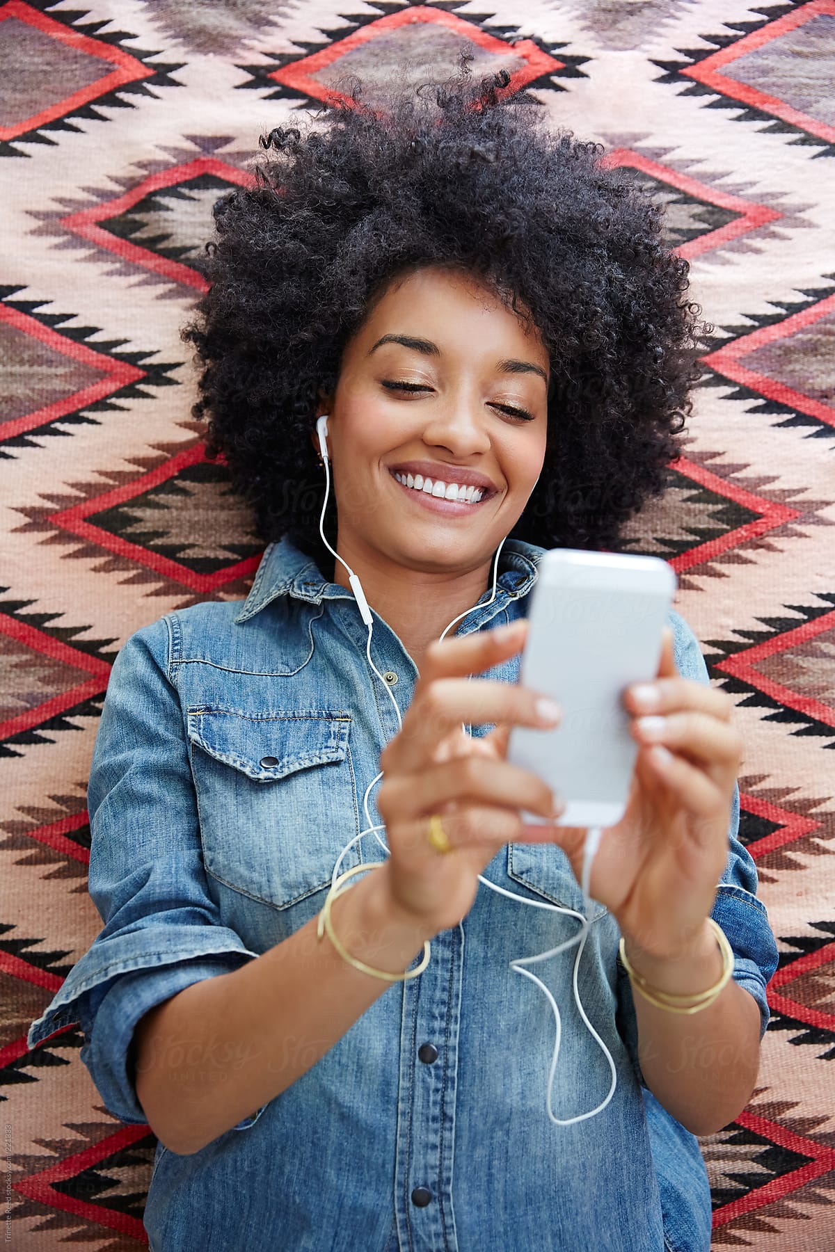 African American Woman Listening To Music On Cell Phone By Stocksy Contributor Trinette Reed