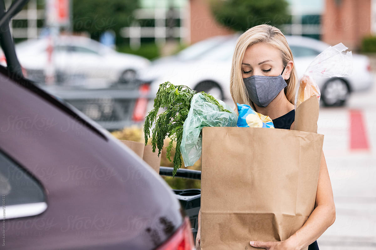 Woman Wearing Face Mask Puts Shopping Bags In Car
