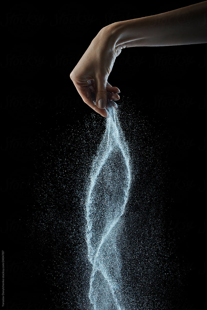 Falling salt from woman\'s hand on a black background, copy space.