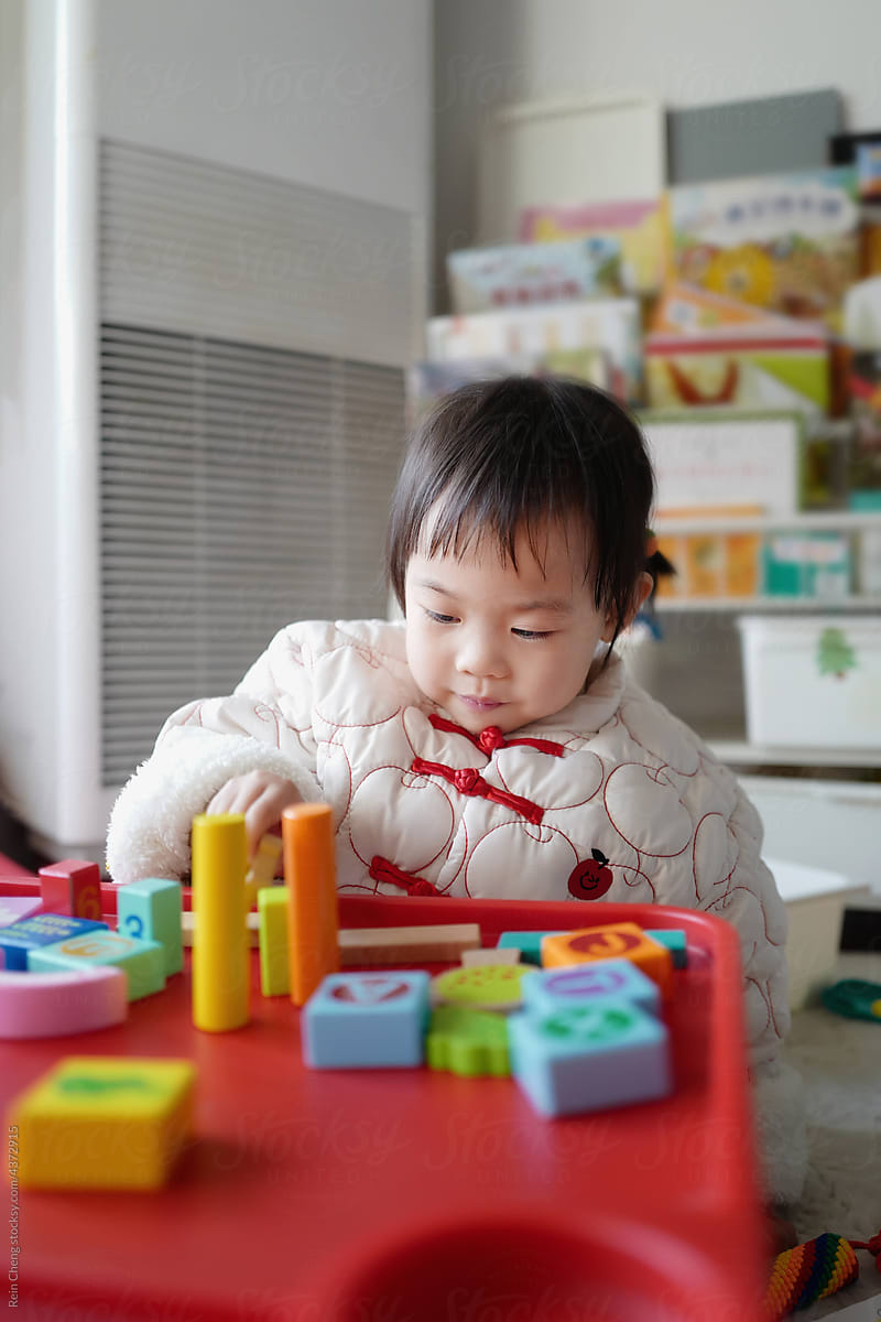 Asian baby builds blocks alone