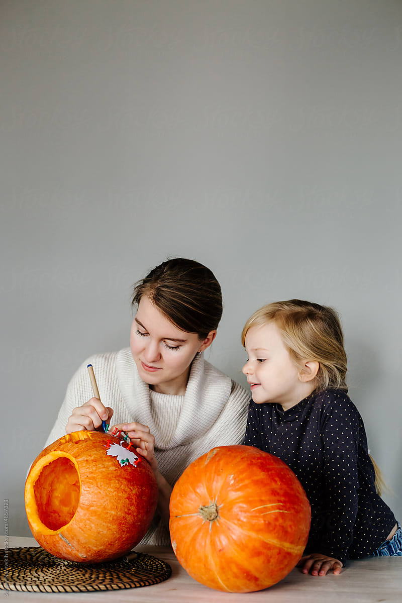 Mother and daughter outlining stencil on pumpkin