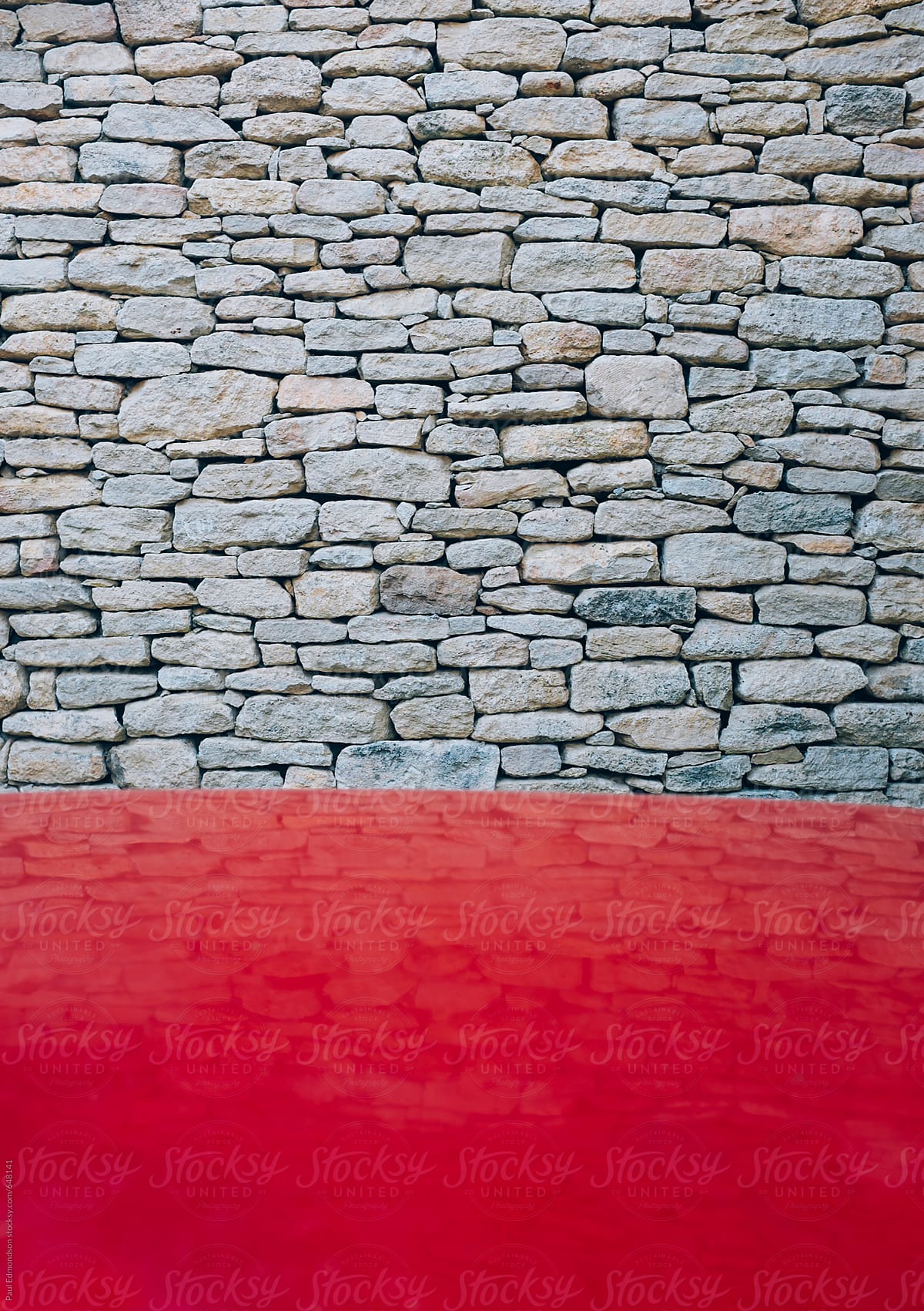 Red hood of car in foreground, old stone wall in background, Provence, France