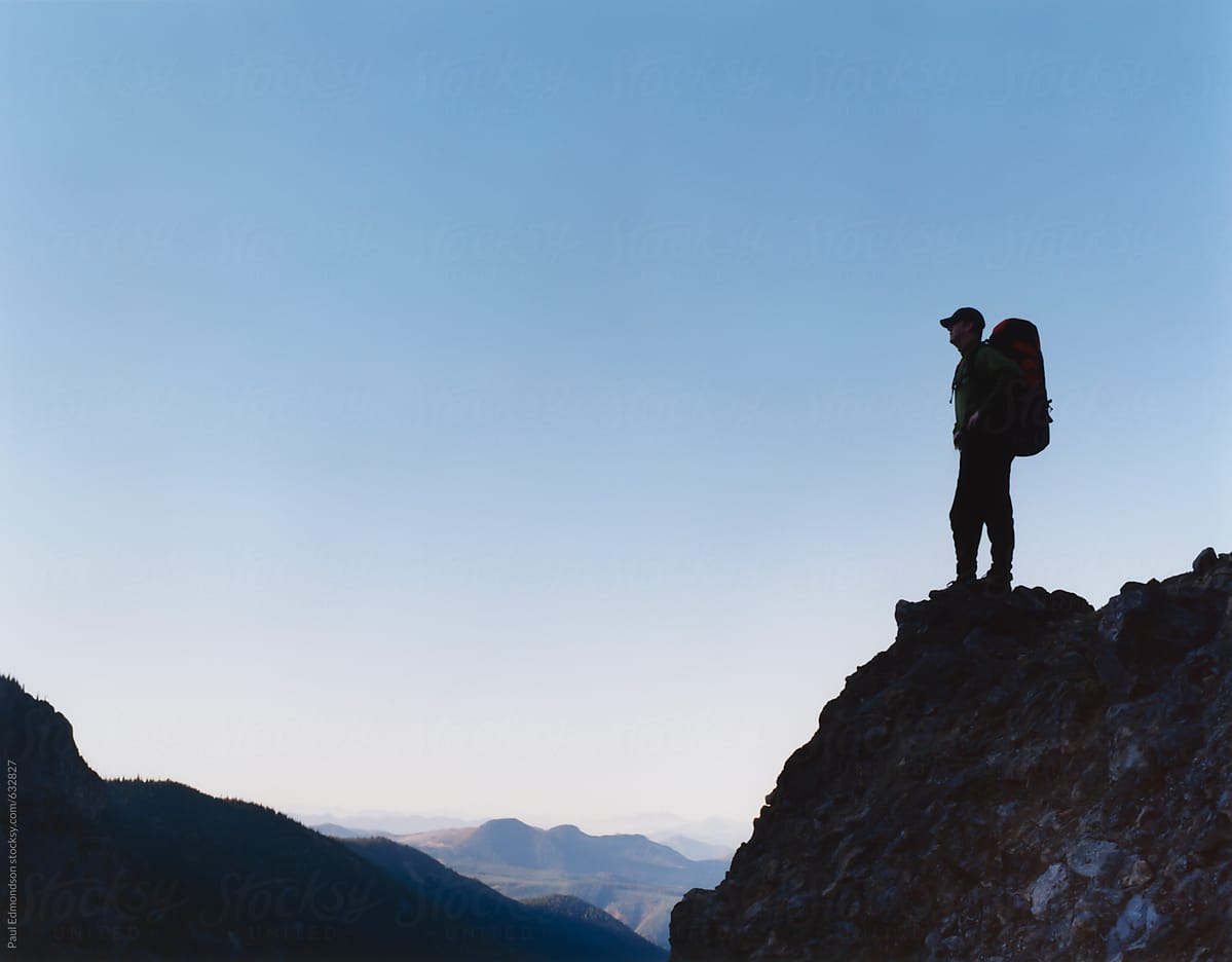 Male backpacker standing on edge of cliff, taking in view
