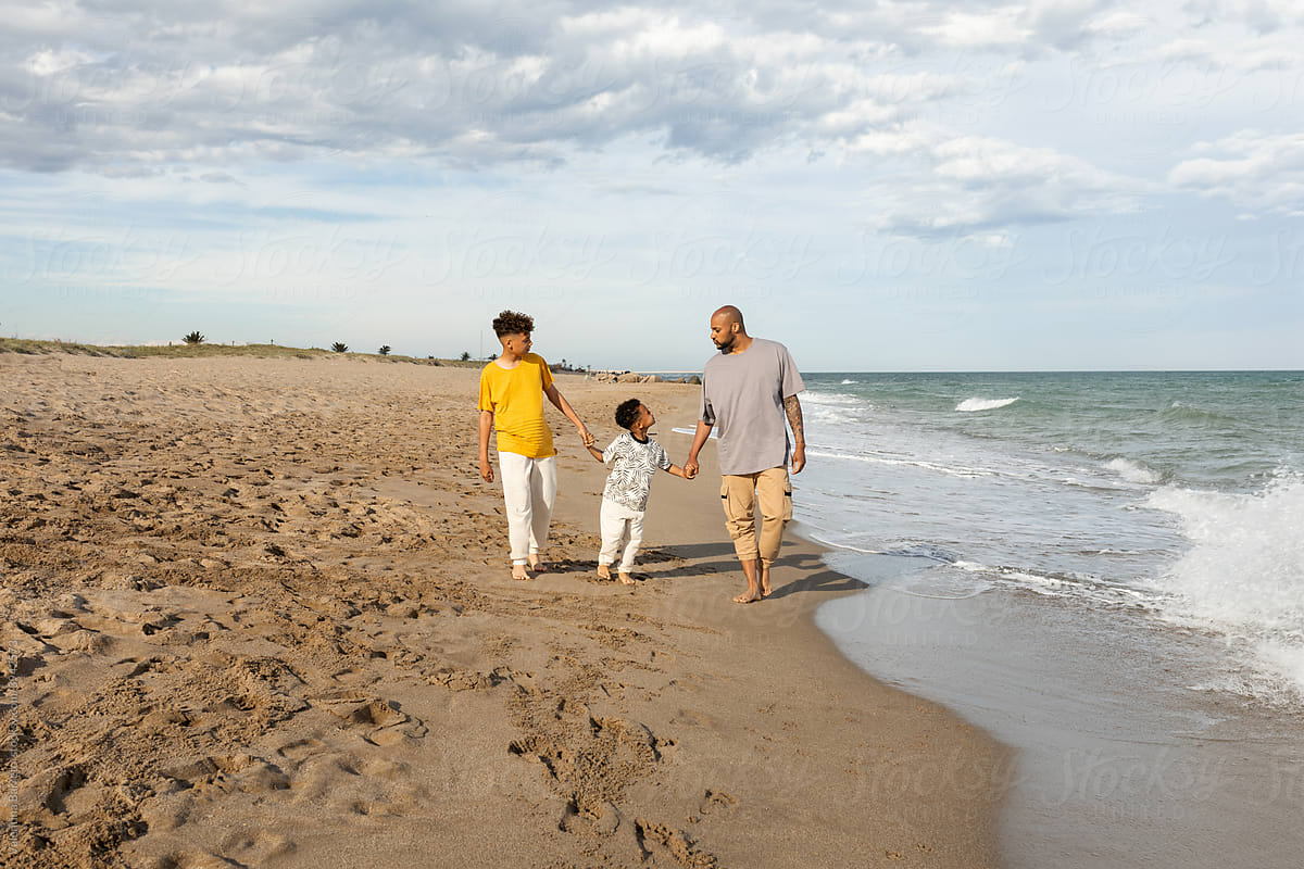 Beautiful family walking by the beach shore
