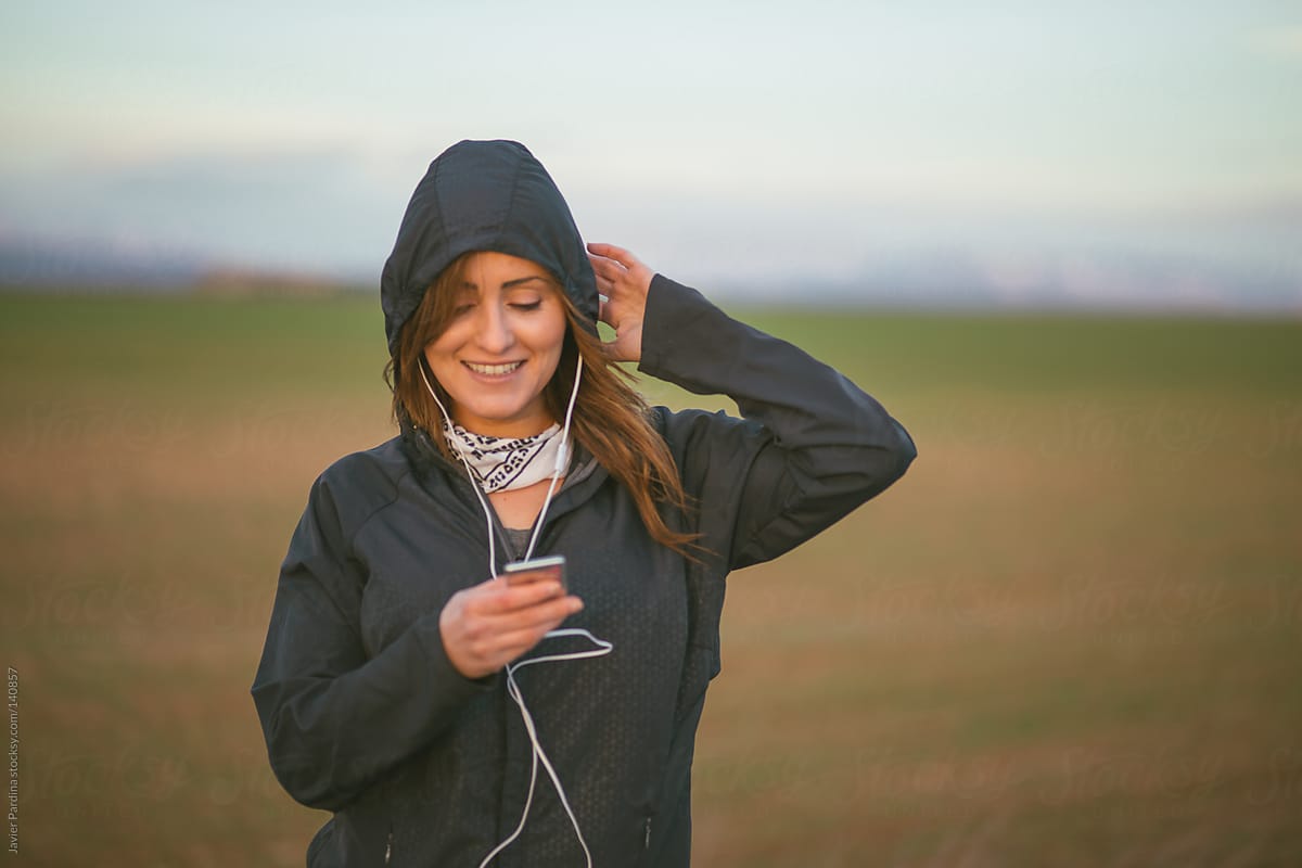 young woman listening to music while exercising in nature.